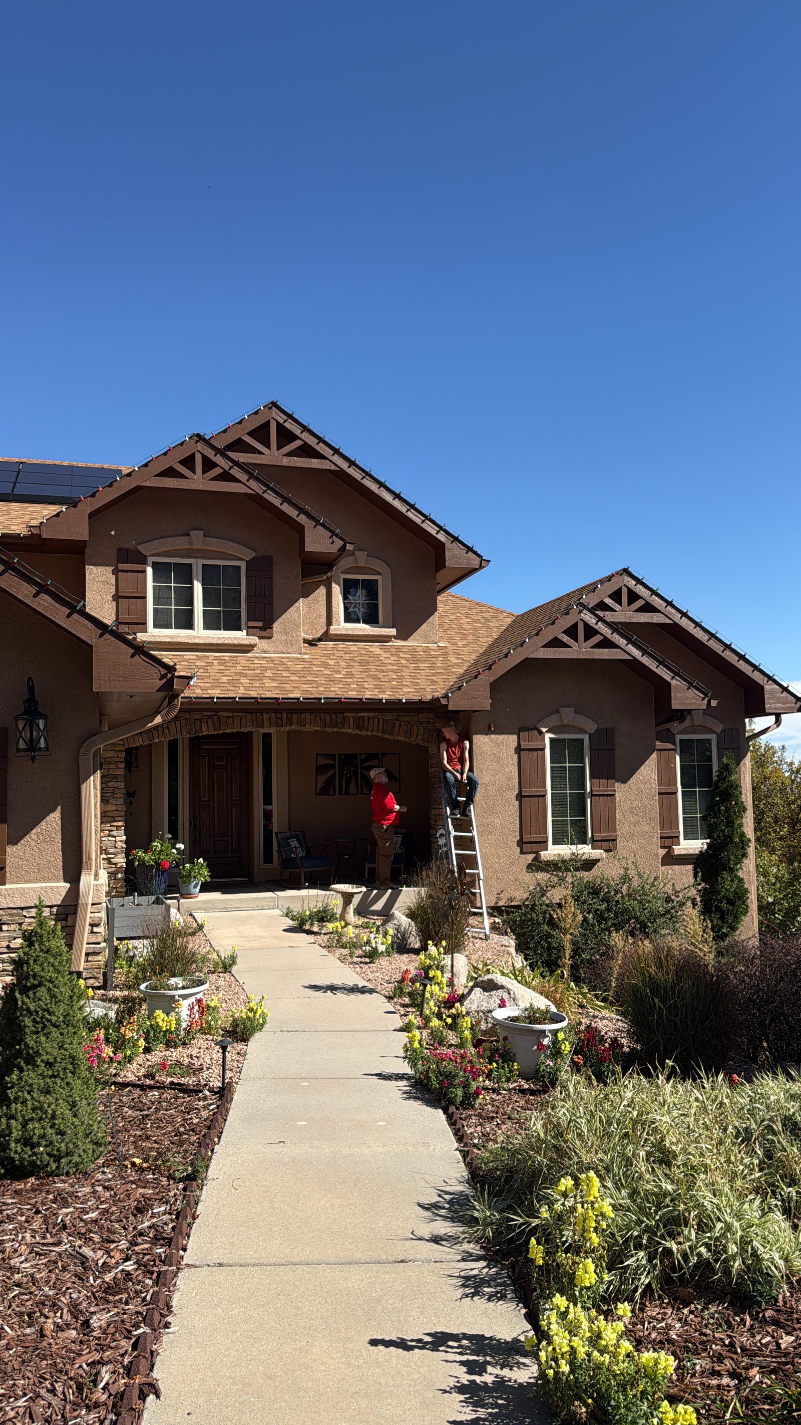 Christmas light installation in progress on a tan stucco two-story residential home Christmas light installation in progress on a tan stucco two-story residential home