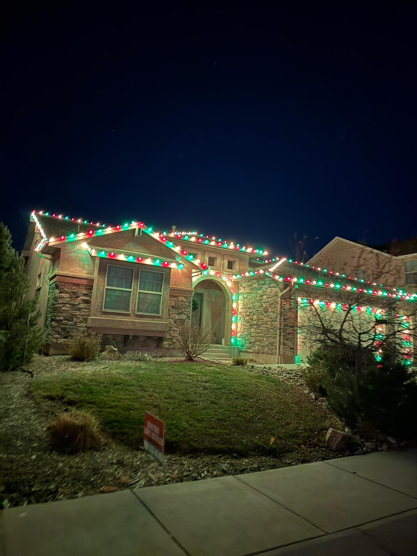 Multicolor holiday display Multicolor Christmas lights on a two-story home with roofline and landscape holiday lighting